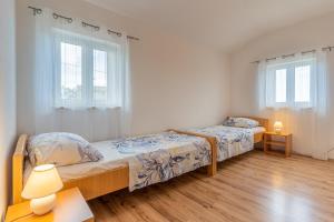 two beds in a bedroom with two windows at Apartment Jurasić in Orlec
