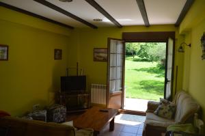 ein Wohnzimmer mit einem Sofa, einem Tisch und einer Tür in der Unterkunft Apartamentos rurales Casa Rosi in Ranón