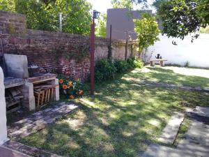um jardim com um banco e uma parede de tijolos em Sueños Cumplidos Chascomús em Chascomús