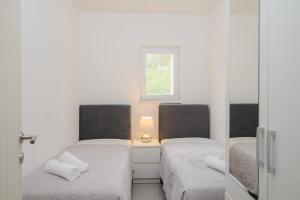 two beds in a small room with a window at Apartments Pelja in Trogir
