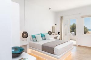 a white bedroom with a bed and a table at Elysium Beachfront Residences by kalais - A 10 Minute Drive Away From Naxos Town in Plaka