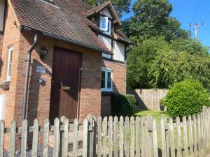 a house with a white fence and a wooden door at Honeysuckle Cottage in Hereford