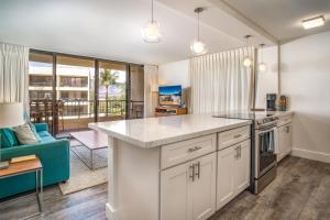 cocina con armarios blancos y sofá azul en Sugar Beach 502 condo, en Kihei