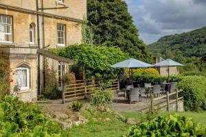 a garden with tables and umbrellas in front of a building at Best Western Limpley Stoke Hotel in Bath