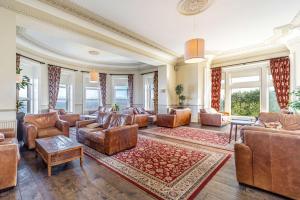 a living room with leather furniture and large windows at Best Western Walton Park Hotel in Clevedon