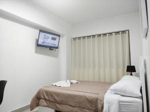 1 dormitorio con 1 cama y TV en la pared en Maxy's Inn Hotel & Suite, en Lima