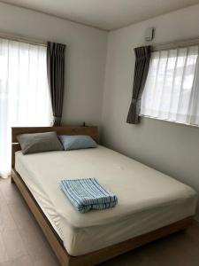 Schlafzimmer mit einem großen Bett mit weißer Bettwäsche und Fenstern in der Unterkunft Blue House in Nago