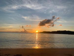 a sunset on the beach with the sun setting at Blue House in Nago +3 photos