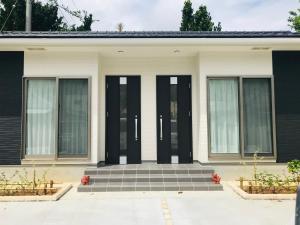 a white house with black doors and windows at Blue House in Nago