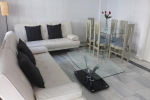 ein Wohnzimmer mit einem weißen Sofa und einem Glastisch in der Unterkunft Los Colimbos in Torremolinos