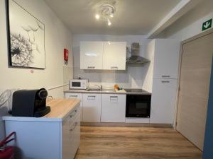 a small kitchen with white cabinets and a microwave at Gîtes de la Croisette 2 in Dinant