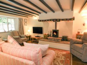 a living room with a fireplace with two couches and a tv at 2 Storrs Cottages in Carnforth