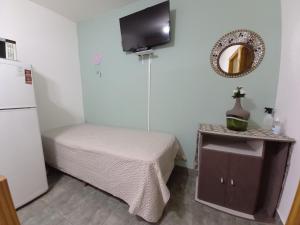 um pequeno quarto com uma cama e uma televisão na parede em Departamentos Buen Pasar em Ushuaia