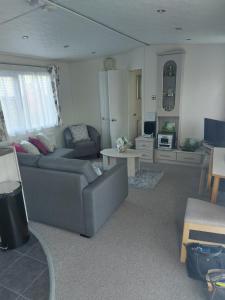 sala de estar con sofá y mesa en Summer Lodge lovely big caravan in Hastings sleeps 6 free WiFi in caravan en St. Leonards