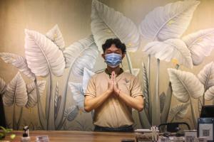 Een man met een masker die bidt voor een muur. bij Larimar Hotel & Resort in Phnom Penh