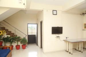 a room with a tv on a wall with plants at Satyam Villa 5Bhk Lonavala in Lonavala