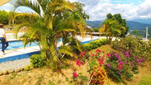 una palma accanto a una piscina con fiori di Villa Maria Casa Campestre a San Gil Altre 37 foto