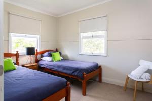 a bedroom with two beds and two windows at Riverview Cottage in Ipswich