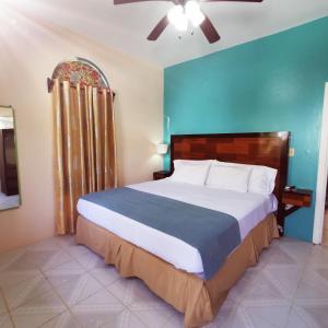 a bedroom with a large bed with a blue wall at BELIZE TROPICAL DREAM VILLAS in San Pedro