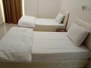 2 Betten in einem Zimmer mit weißer Bettwäsche und Kissen in der Unterkunft JANDOUL SALALAH جندول صلاله in Salalah