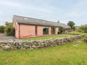 a house with a stone wall in front of it at Llofft Yr Yd in Caernarfon