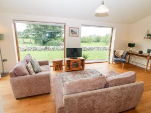 a living room with two couches and a tv at Llofft Yr Yd in Caernarfon