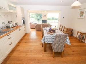 een keuken en een woonkamer met een tafel met een tafelkleed bij Llofft Yr Yd in Caernarfon