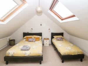 2 bedden in een zolderslaapkamer met dakramen bij Llofft Yr Yd in Caernarfon