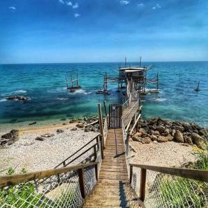 a wooden pathway to the ocean with a pier at Ok Home Pescara Rooms in Pescara