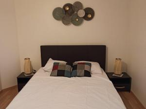 een bed met twee kussens en een klok aan de muur bij Appartement Châteauroux, 3 pièces, 4 personnes - FR-1-591-191 in Châteauroux