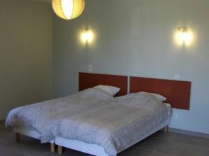 łóżko w sypialni z dwoma światłami na ścianie w obiekcie Gîte Contemporain en Écovillage avec Grande Terrasse et Proximité Attractions, 3 Chambres, PMR - FR-1-584-123 w mieście Ville-sur-Yron