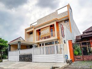 uma casa com uma cerca branca em frente em Super OYO 90383 Avisha Guest House Syariah em Malang