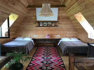 two beds in a wooden room with a rug at Breb s Cosy Barn in Breb