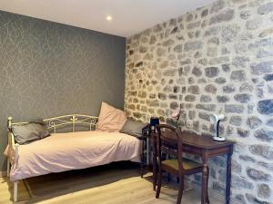 a bedroom with a bed and a desk and a stone wall at Gîte Blavozy, 2 pièces, 3 personnes - FR-1-582-57 in Blavozy