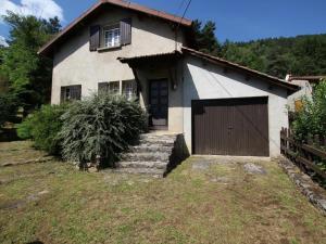 a white house with a garage and a fence at Maison familiale avec terrasse, grand terrain et proche de la rivière - Alleyras, 6 pers. - FR-1-582-244 in Alleyras