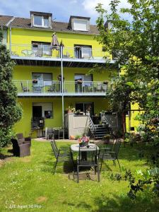 a yellow building with a table and chairs in the yard at 5x Fuchs-Dobry Balkon-Apartments 40qm-65qm in Oberhausen