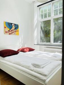 uma grande cama branca num quarto com duas janelas em aday - Aalborg mansion - Open bright apartment with garden em Aalborg