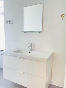 W białej łazience znajduje się umywalka i lustro. w obiekcie aday - Aalborg mansion - Open bright apartment with garden w Aalborgu