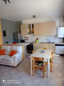 eine Küche und ein Wohnzimmer mit einem weißen Sofa und einem Tisch in der Unterkunft Da nonna Pina in Cossogno