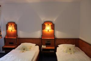 Dos camas en una habitación con dos luces. en Hotel Höfler B&B, en Núremberg