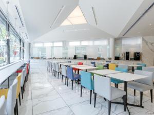 a cafeteria with tables and chairs and windows at Fukuoka U-BELL Hotel in Fukuoka