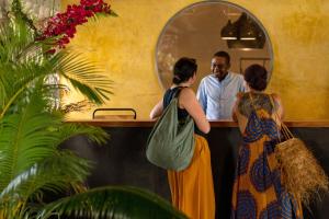 a man standing at a counter with two women at Casa Beach Hotel "Casa Del Mar" in Jambiani