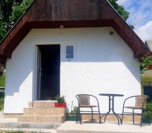 2 Stühle und ein Tisch vor einem Haus in der Unterkunft Durmitorski konak in Žabljak