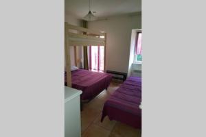 1 Schlafzimmer mit 2 Betten und lila Bettwäsche in der Unterkunft Maison au centre de St Jean du Gard in Saint-Jean-du-Gard