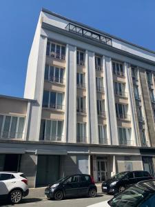 un grand bâtiment blanc avec des voitures garées devant lui dans l'établissement TY STUDIOS Hyper Centre Ville, à Brest