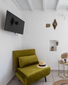 a living room with a green couch and a flat screen tv at Levantes House Mykonos in Ano Mera