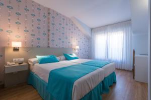 a bedroom with a large bed with blue sheets at Hotel Bemon Playa in Somo