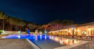 a swimming pool at night with a resort at Arcobaleno Village in Marina di Bibbona