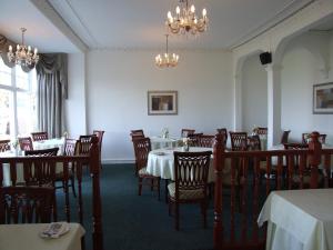 a dining room with tables and chairs and chandeliers at The Victoria Hotel in Rothesay