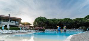 a swimming pool with chairs and people in a resort at Arcobaleno Village in Marina di Bibbona